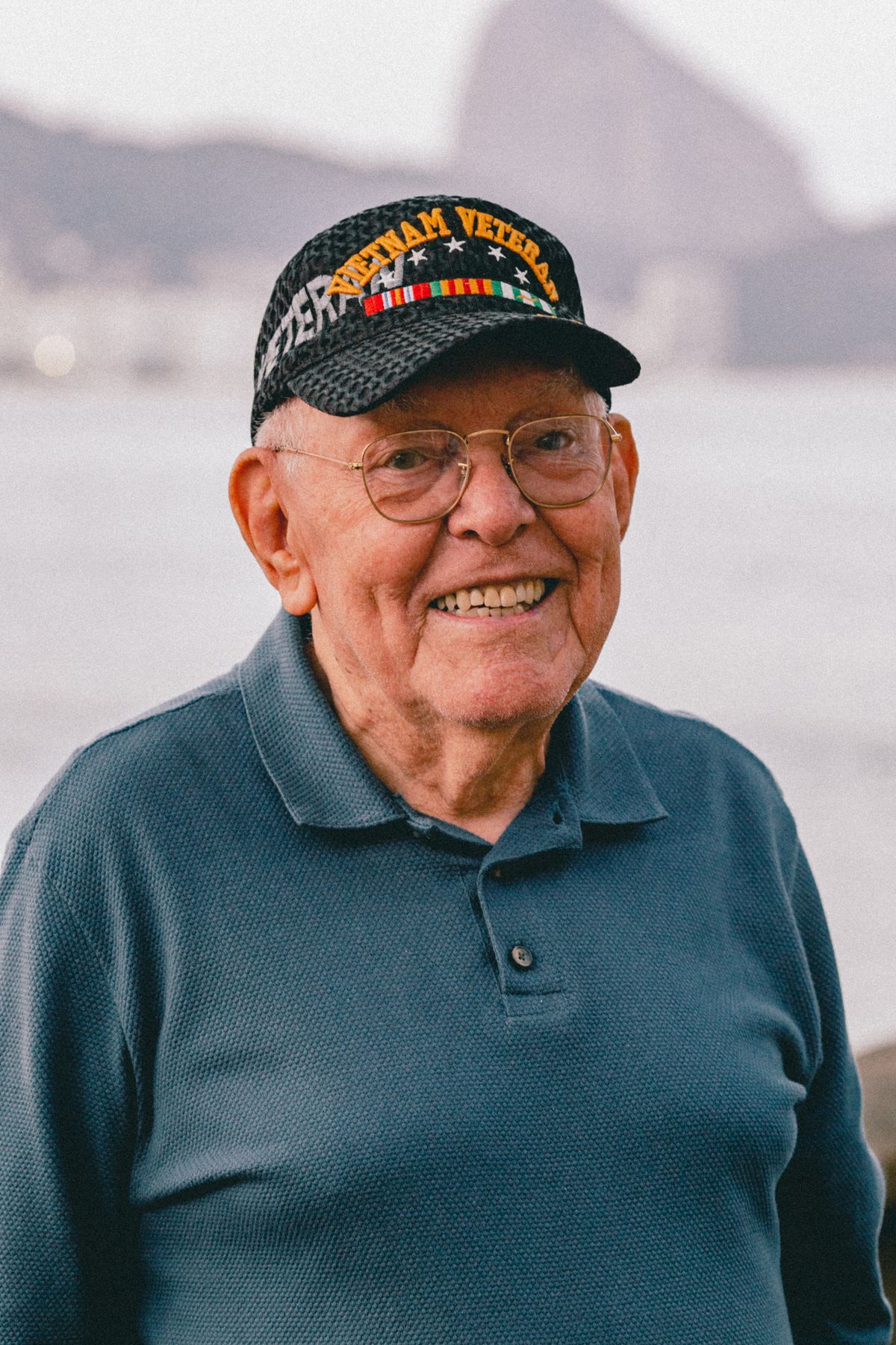 A smiling U.S. veteran wearing a veteran ball cap